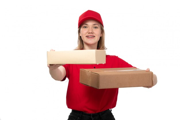 Une vue de face jeune femme ouvrière de messagerie de service de livraison de nourriture souriant tenant des boîtes avec de la nourriture sur blanc