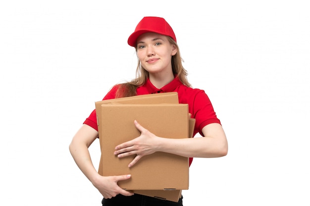 Une vue de face jeune femme ouvrière de messagerie de service de livraison de nourriture souriant tenant des boîtes avec de la nourriture sur blanc