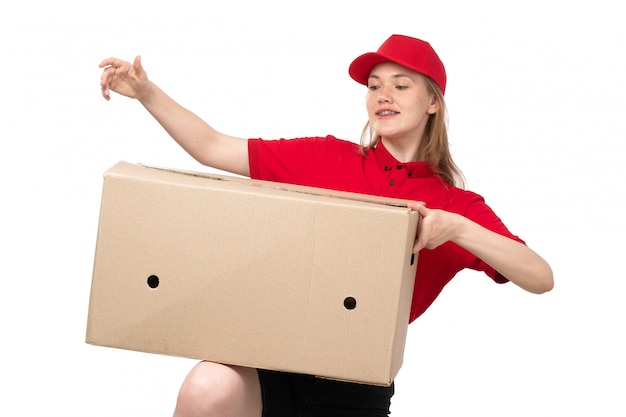 Une vue de face jeune femme ouvrière de messagerie de service de livraison de nourriture souriant tenant une énorme boîte de livraison sur blanc