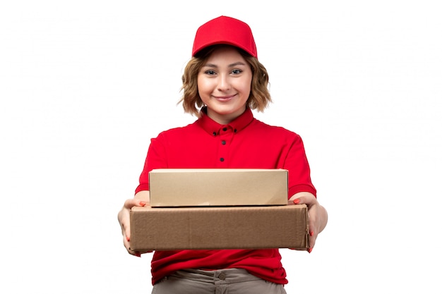 Une vue de face jeune femme ouvrière de messagerie de service de livraison de nourriture tenant des colis de livraison de nourriture souriant sur blanc