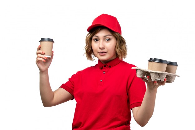 Une Vue De Face Jeune Femme Ouvrière De Messagerie De Service De Livraison De Nourriture Tenant Des Tasses à Café Sur Blanc