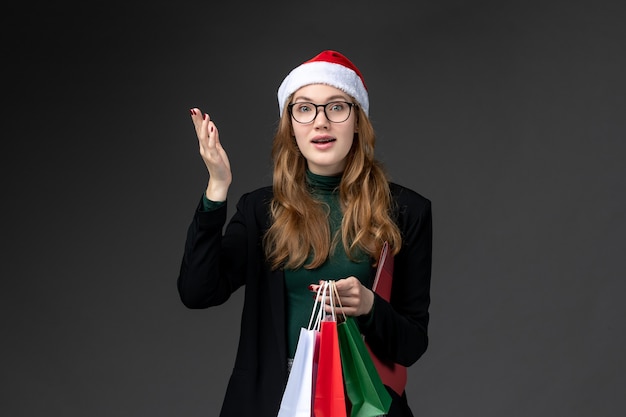 Vue de face jeune femme avec des paquets sur mur sombre cadeau nouvel an vacances actuelles