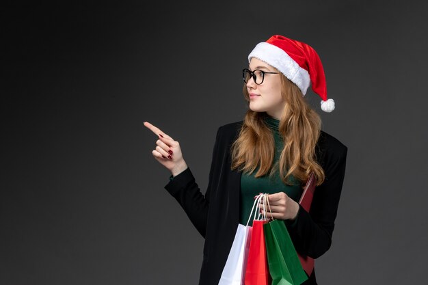 Vue de face jeune femme avec des paquets sur un mur sombre cadeau de nouvel an