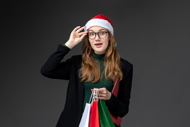 Vue de face jeune femme avec des paquets sur le sol sombre cadeau nouvel an cadeau