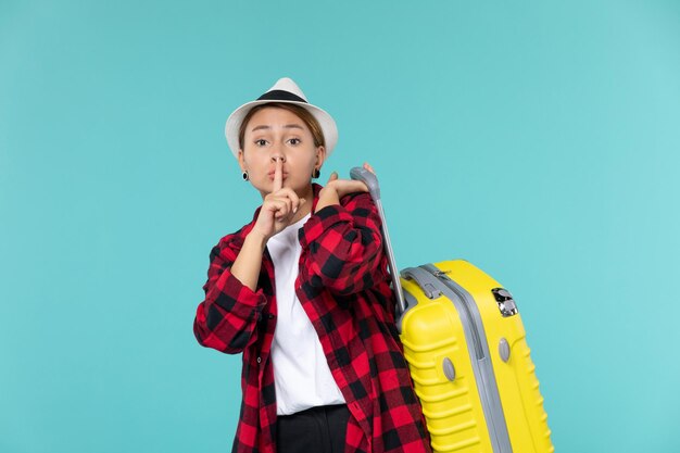 Vue de face jeune femme partant en vacances avec son sac jaune sur l'espace bleu clair