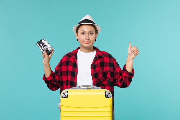 Vue de face jeune femme partant en voyage et tenant la caméra sur l'espace bleu