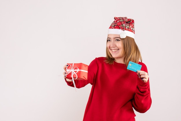 Vue de face jeune femme avec petit cadeau de Noël et carte bancaire