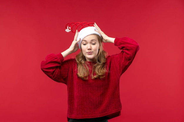 Vue de face jeune femme portant un bonnet de noel rouge sur un bureau rouge vacances noël