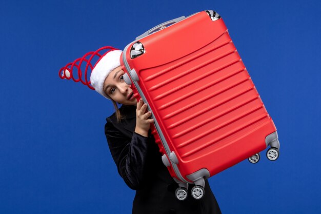 Vue de face jeune femme portant gros sac rouge sur bureau bleu couleur vacances nouvel an vacances