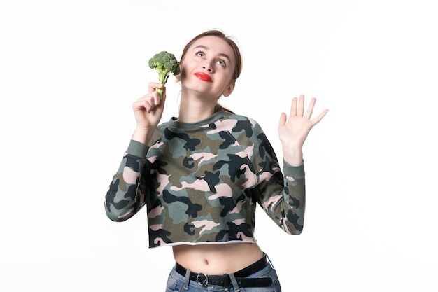 Vue de face jeune femme posant avec du brocoli vert sur fond blanc régime alimentaire aliments santé déjeuner couleurs horizontales pain corps salade repas