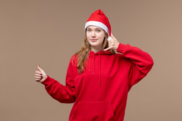 Vue de face jeune femme posant avec sourire sur fond marron vacances d'émotion de Noël