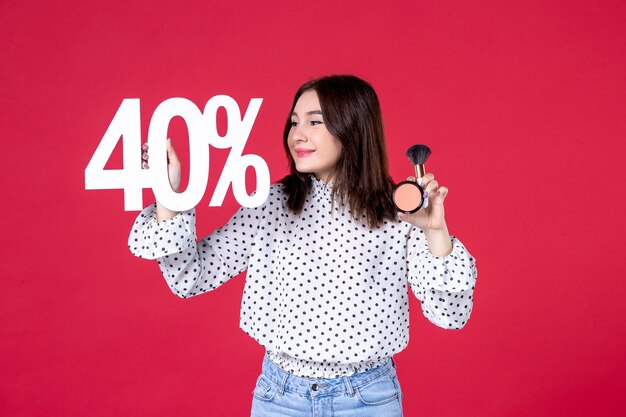 Vue de face jeune femme avec de la poudre de gland pour le maquillage et l'écriture sur le mur rouge