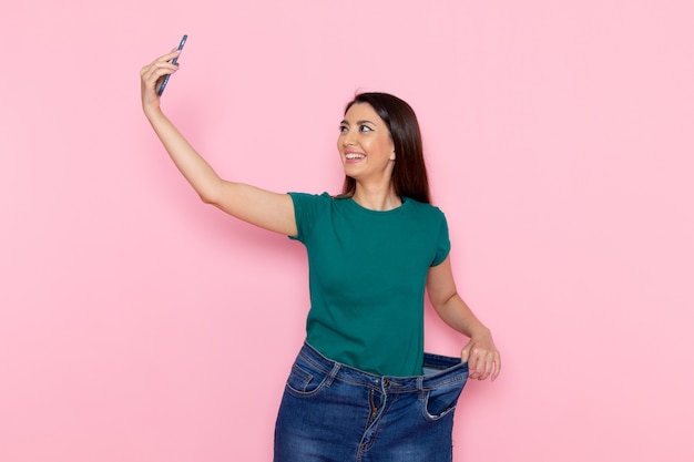 Vue de face jeune femme prenant selfie sur mur rose exercice sport entraînement athlète taille beauté