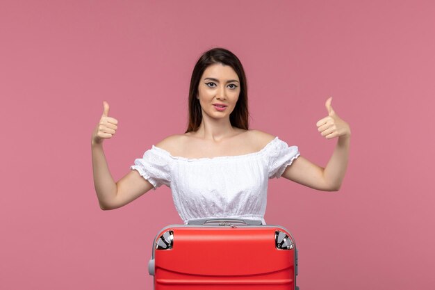 Vue de face jeune femme prépare pour des vacances sur fond rose clair vacances à l'étranger voyage voyage voyage