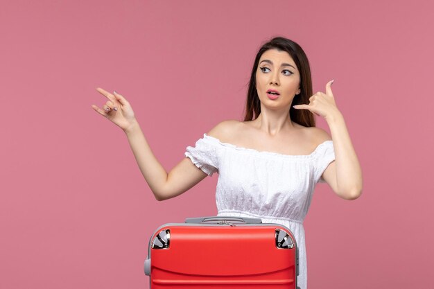 Vue de face jeune femme prépare pour des vacances sur fond rose vacances à l'étranger voyage voyage voyage