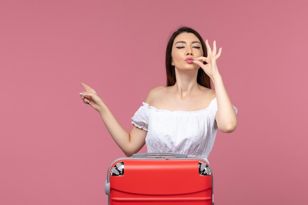 Vue de face jeune femme prépare pour les vacances avec son sac rouge sur le bureau rose voyage à l'étranger voyage voyage en mer