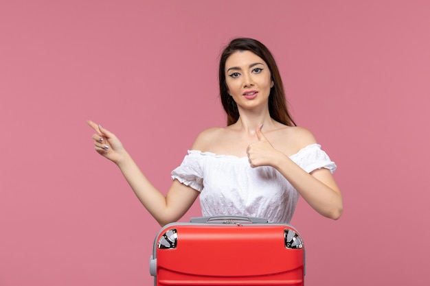 Vue de face jeune femme prépare pour les vacances avec son sac rouge sur le fond rose voyage à l'étranger voyage voyage en mer