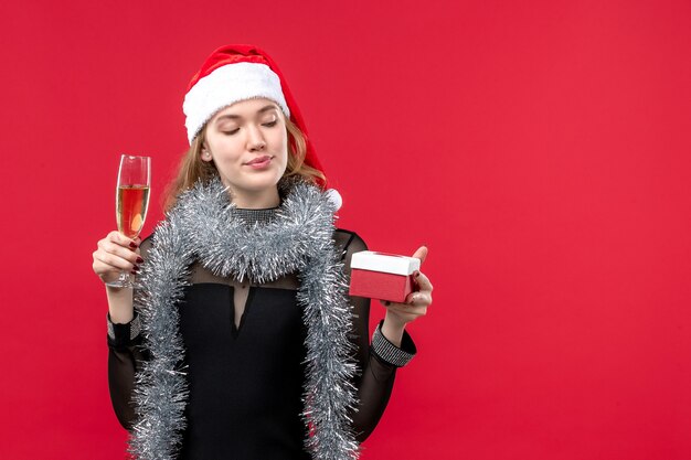 Vue de face jeune femme avec présent célébrant sur le mur rouge vacances Noël couleur