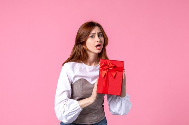 Vue de face jeune femme avec présent dans un emballage rouge sur fond rose mars argent égalité sensuelle horizontale femme cadeaux