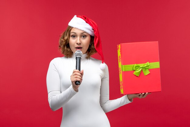 Vue de face de la jeune femme avec présent et micro sur rouge