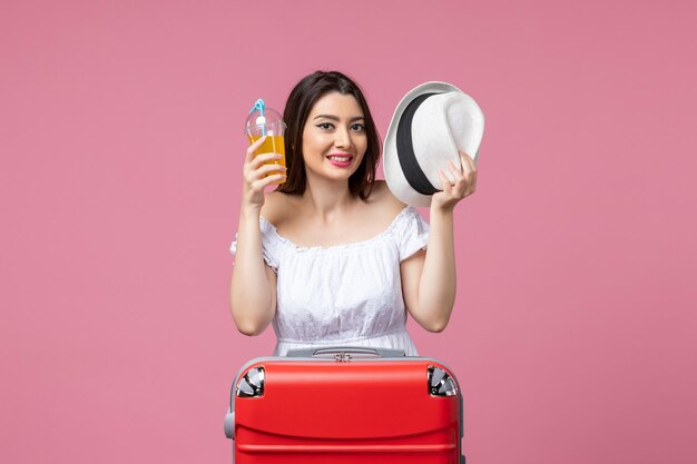 Vue de face jeune femme profitant du temps en vacances sur le sol rose couleur d'été voyage de vacances voyage de chaleur