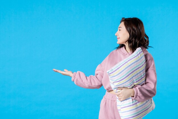 Vue de face jeune femme en pyjama rose avec oreiller sur lit de couleur bleu nuit repos sommeil sommeil insomnie