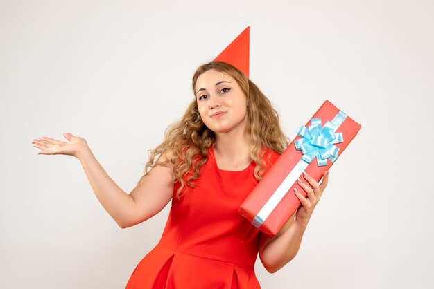 Vue de face jeune femme en robe rouge célébrant Noël avec présent