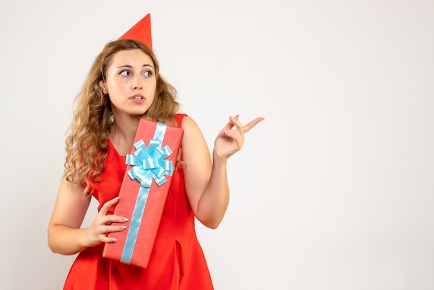 Vue de face jeune femme en robe rouge célébrant Noël avec présent