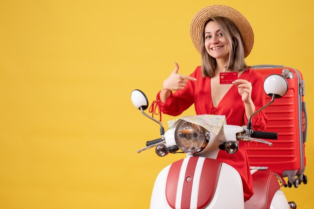 Vue De Face Jeune Femme En Robe Rouge Pointant Sur Carte Bancaire Sur Cyclomoteur