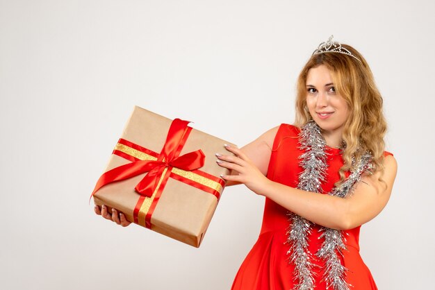 Vue de face jeune femme en robe rouge tenant le cadeau de Noël