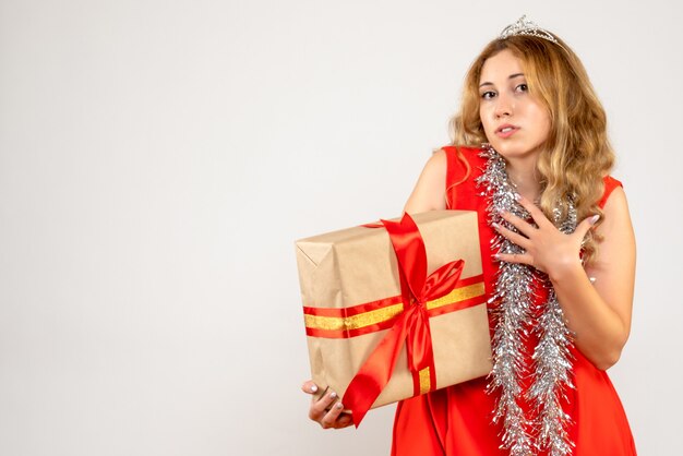 Vue de face jeune femme en robe rouge tenant le cadeau de Noël