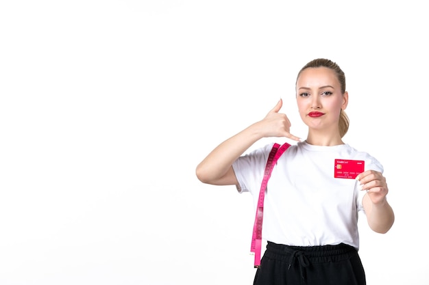 Vue de face jeune femme avec ruban à mesurer et carte de crédit sur fond blanc argent perdre la beauté de la banque mesurant le corps de la peau amincissant le torse de la hanche