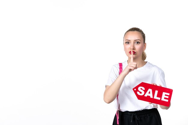 Vue de face jeune femme avec ruban à mesurer et plaque signalétique de vente sur fond blanc mesurant la peau de la hanche du torse du centre commercial du corps minceur