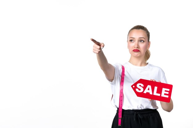 Vue de face jeune femme avec ruban à mesurer et plaque signalétique de vente sur fond blanc mesurant shopping corps taille centre commercial torse peau hanche poids couleurs