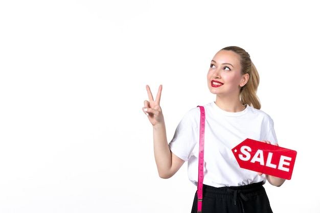 Vue de face jeune femme avec ruban à mesurer et plaque signalétique de vente sur une surface blanche