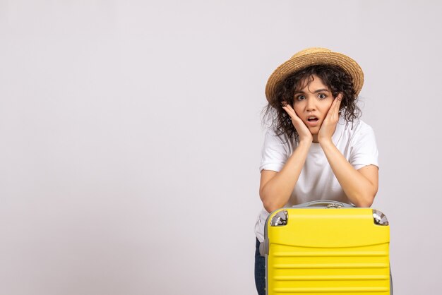 Vue de face jeune femme avec sac jaune se préparant au voyage sur fond blanc couleur vacances voyage vol avion reste