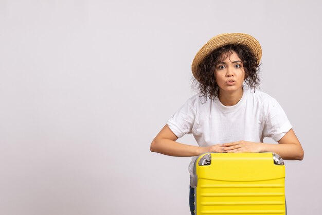 Vue de face jeune femme avec sac jaune se préparant au voyage sur fond blanc couleur vacances voyage vol avion touristique