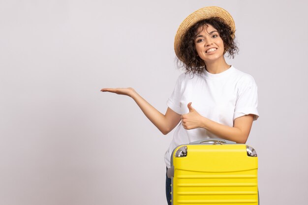 Vue de face jeune femme avec sac jaune se préparant au voyage sur fond blanc vol reste voyage vacances touristiques couleurs avion soleil