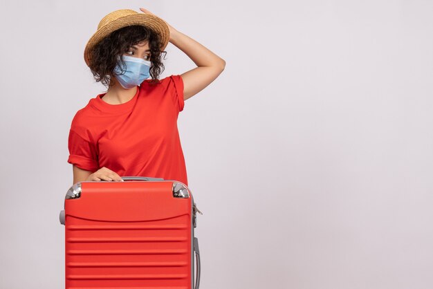 Vue de face jeune femme avec sac en masque sur fond blanc couleur covid- voyage vacances touristiques voyage pandémie du virus du soleil