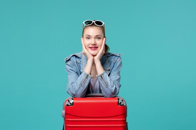 Vue de face jeune femme avec sac de préparation pour les vacances sur l'espace bleu