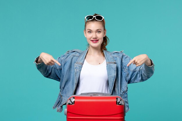 Vue de face jeune femme avec sac de préparation pour les vacances sur l'espace bleu