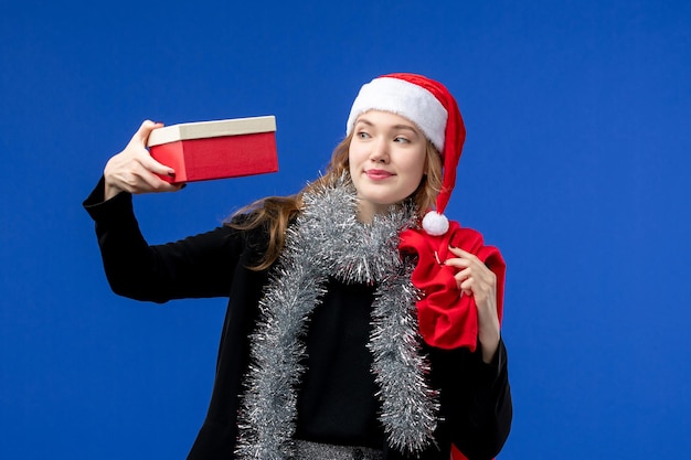 Vue de face d'une jeune femme avec un sac présent et un cadeau sur le mur bleu