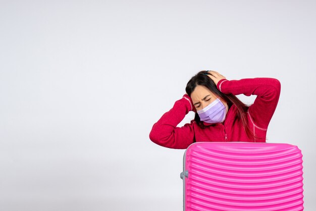 Vue de face jeune femme avec sac rose en masque ayant des maux de tête sur mur blanc