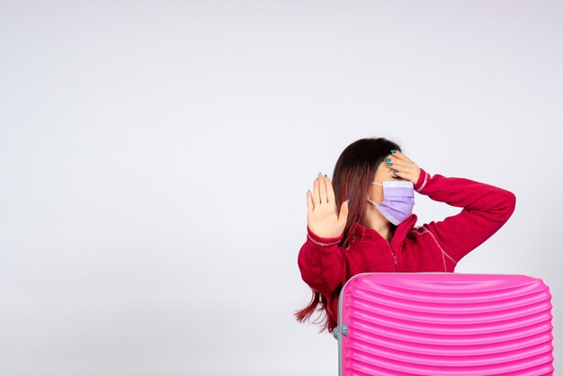 Vue de face jeune femme avec sac rose en masque sur mur blanc vacances pandémie covid- voyage couleur femme