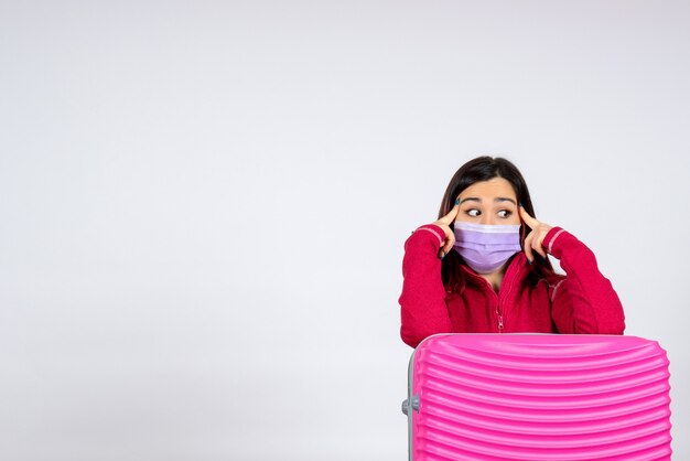 Vue de face jeune femme avec sac rose en masque sur mur blanc vacances virus pandémique covid- couleur femme