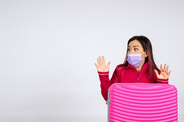 Vue de face jeune femme avec sac rose en masque sur mur blanc virus femme vacances couleur voyage pandémique