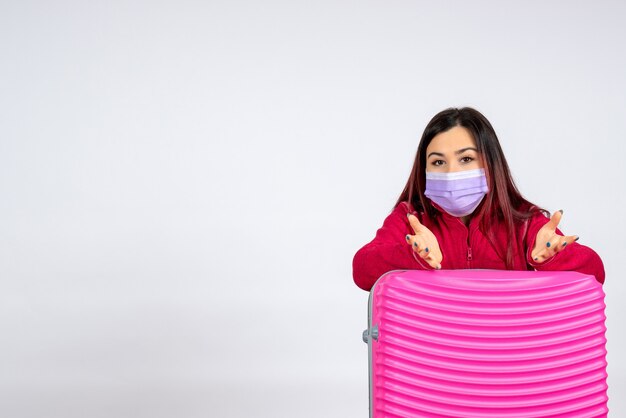 Vue de face jeune femme avec sac rose en masque sur mur blanc virus femme vacances covid- pandémie de voyage couleur