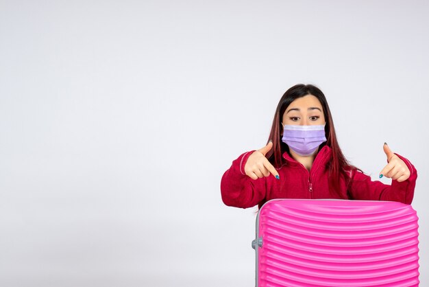 Vue de face jeune femme avec sac rose en masque sur mur blanc virus femme vacances pandémie couleur covid