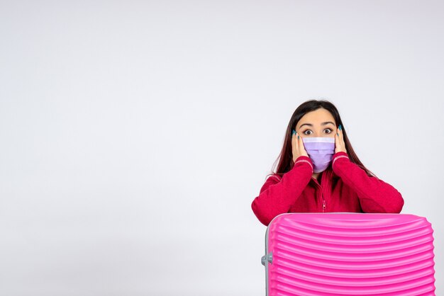 Vue de face jeune femme avec sac rose en masque surpris sur mur blanc vacances virus pandémique femme covid- voyage couleur