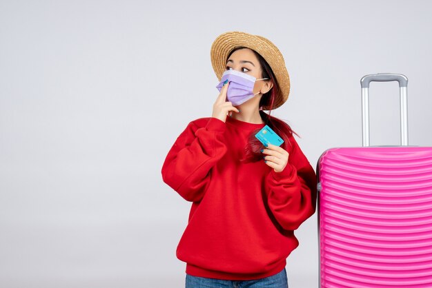 Photo gratuite vue de face jeune femme avec sac rose tenant une carte bancaire en masque sur mur blanc